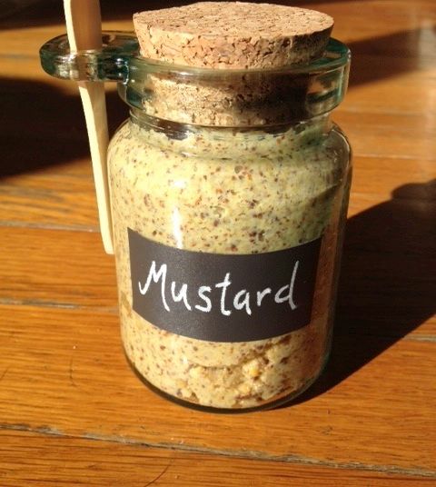 a jar filled with mustard sitting on top of a wooden table