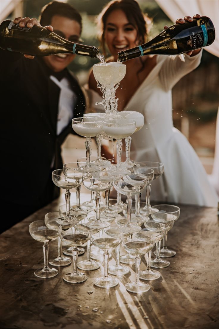 a bride and groom are pouring champagne into wine glasses