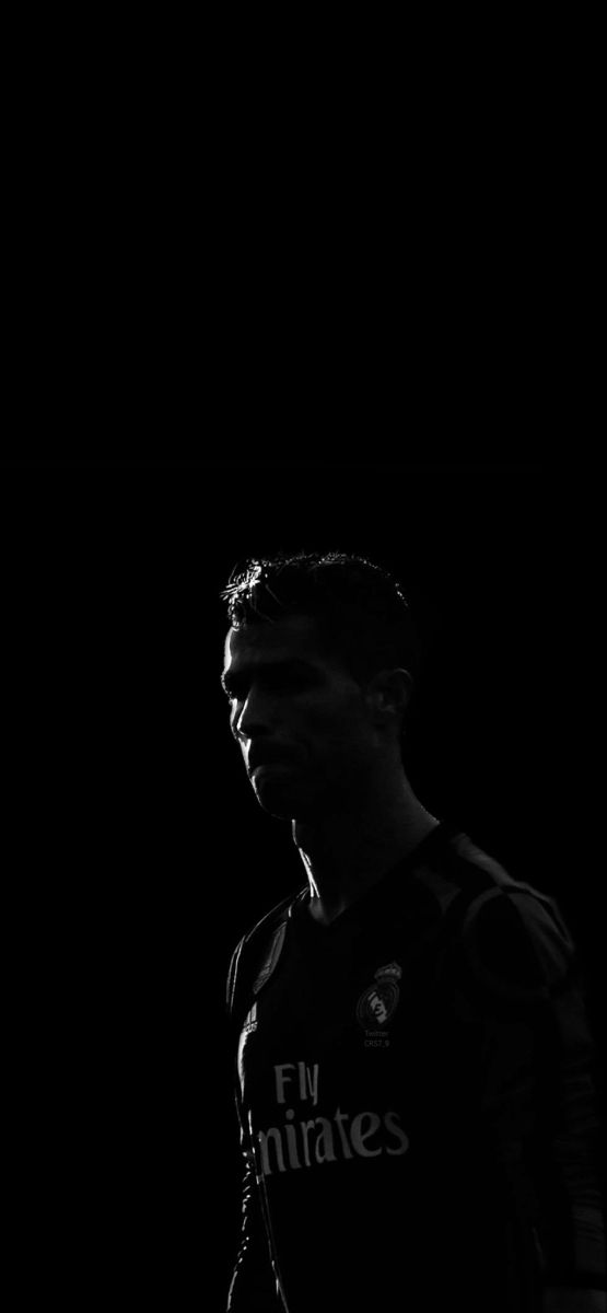 a black and white photo of a soccer player in the dark with his head turned to the side