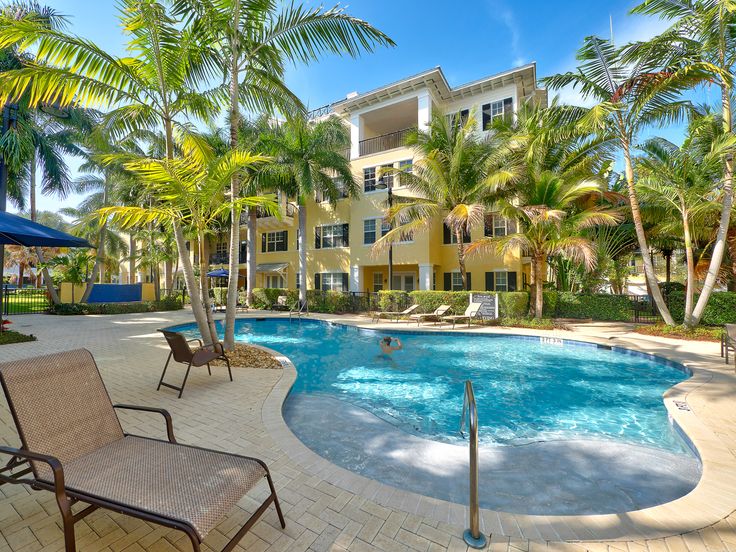 an empty swimming pool surrounded by palm trees and apartment buildings in the backround