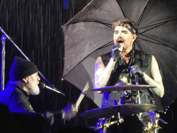 a man holding an umbrella while standing next to a drummer