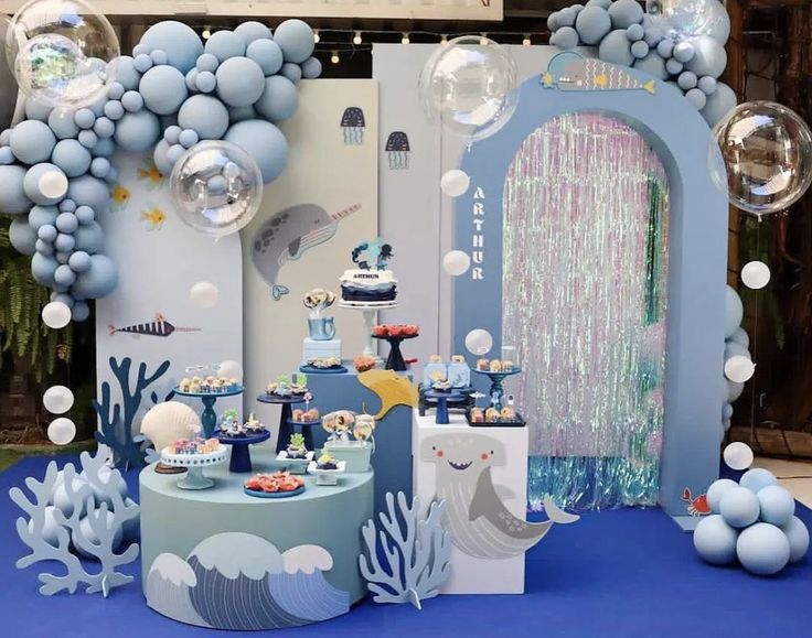 an under the sea themed birthday party with balloons and desserts in blue, white and silver