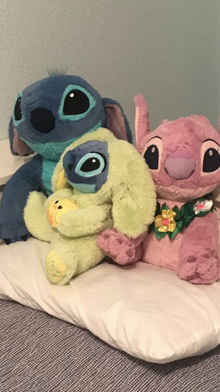 three stuffed animals sitting on top of a pillow