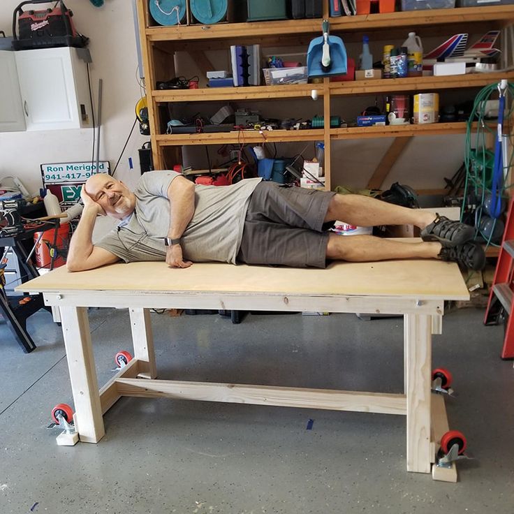 a man laying on top of a work bench