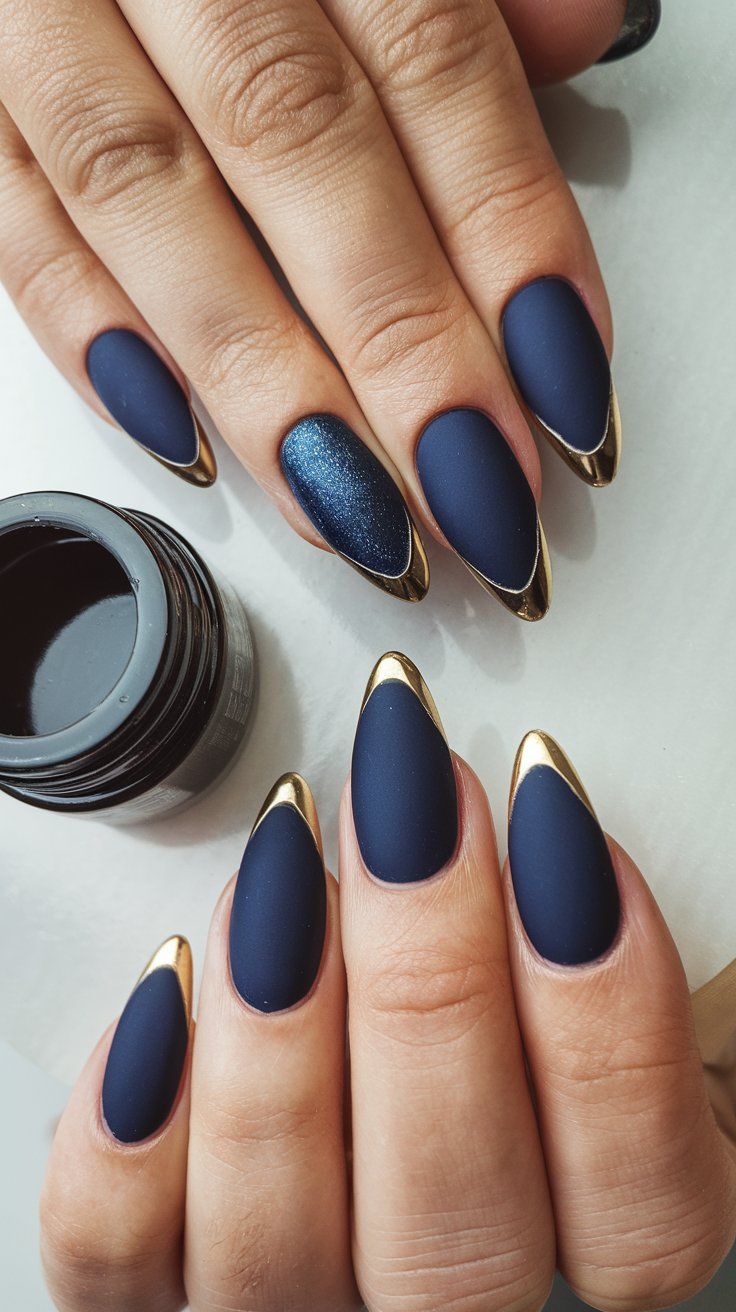 Discover elegance with this exquisite matte navy and gold stiletto nail design! The striking gold tips add a touch of luxury, while the deep navy provides a sophisticated backdrop. Featuring a dazzling blue accent nail, this manicure is perfect for making a bold statement. Try this chic look to elevate your style for any occasion! #NailArt #NailDesign #ChicNails #fallnails #septembernails Navy Blue Nails Matte Art Designs, Sapphire Blue And Gold Nails, Christmas Nails Blue And Gold, Matt Dark Blue Nails, Navy Blue Oval Acrylic Nails, Elegant Blue Nail Designs, Matt Navy Blue Nails, Ravenclaw Inspired Nails, Blue And Gold Chrome Nails