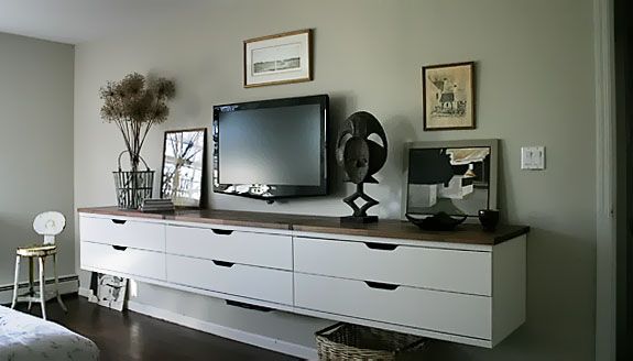 a flat screen tv sitting on top of a white dresser next to a wall mounted television