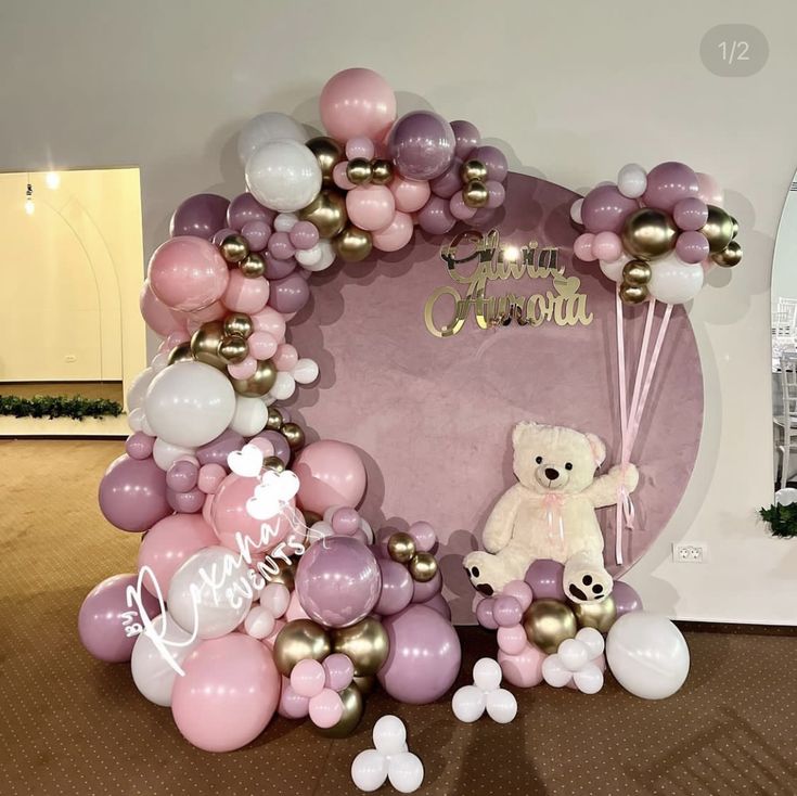 a teddy bear sitting on top of a bunch of balloons