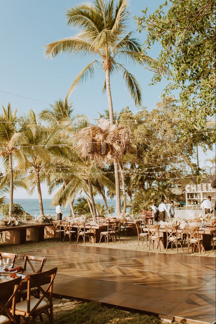 an outdoor dining area with palm trees and tables set up for a party or event