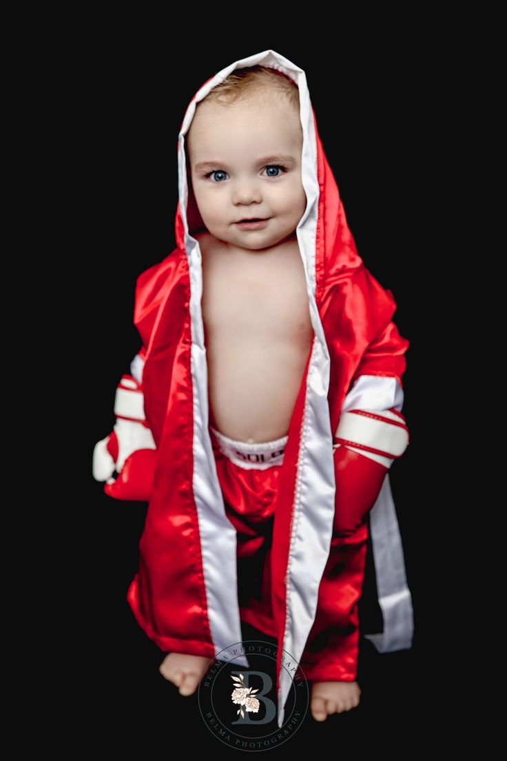 a baby dressed in a red and white outfit with hood on it's head