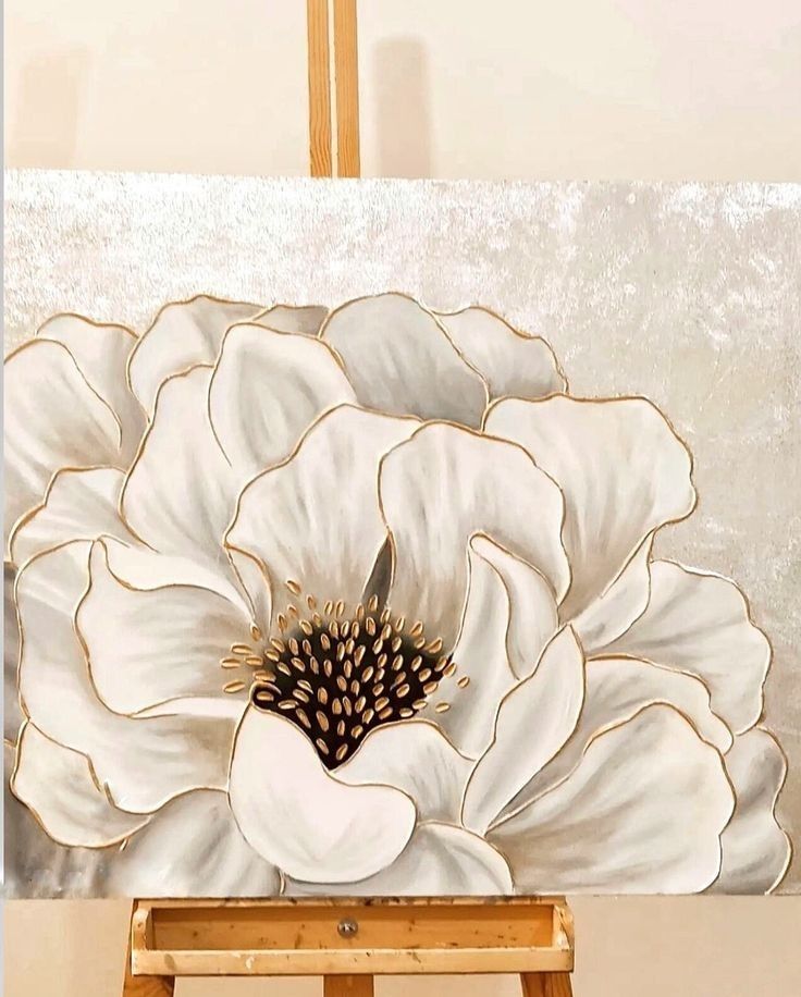 a large white flower painted on an easel