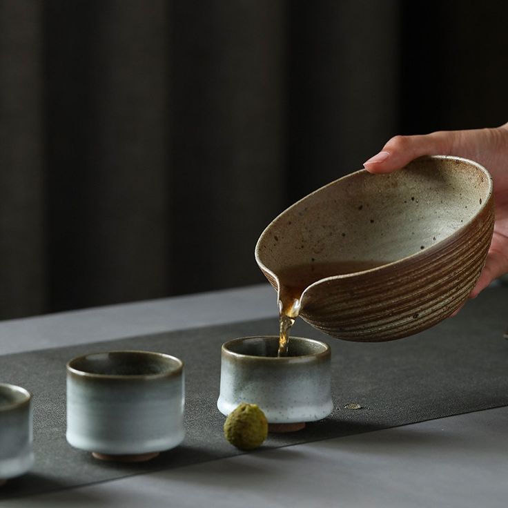 a person pours tea into small cups