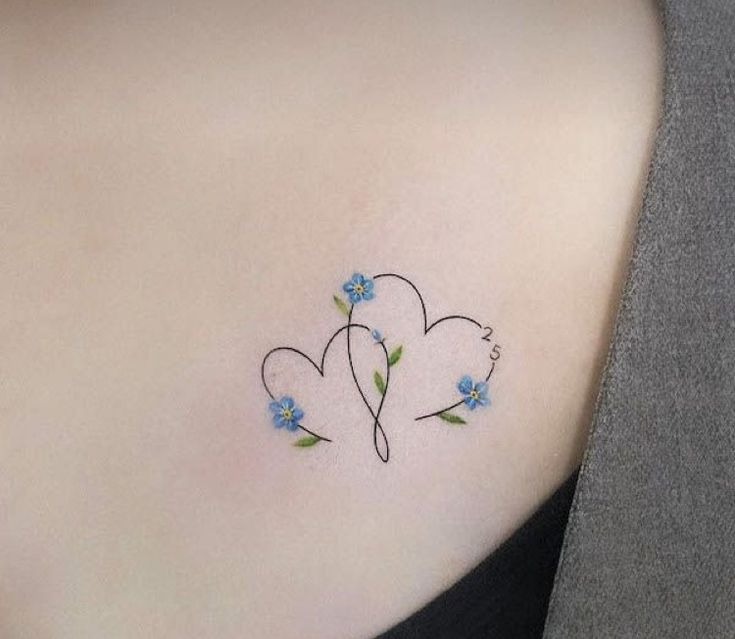 a woman's back shoulder with blue flowers and two hearts on the left side