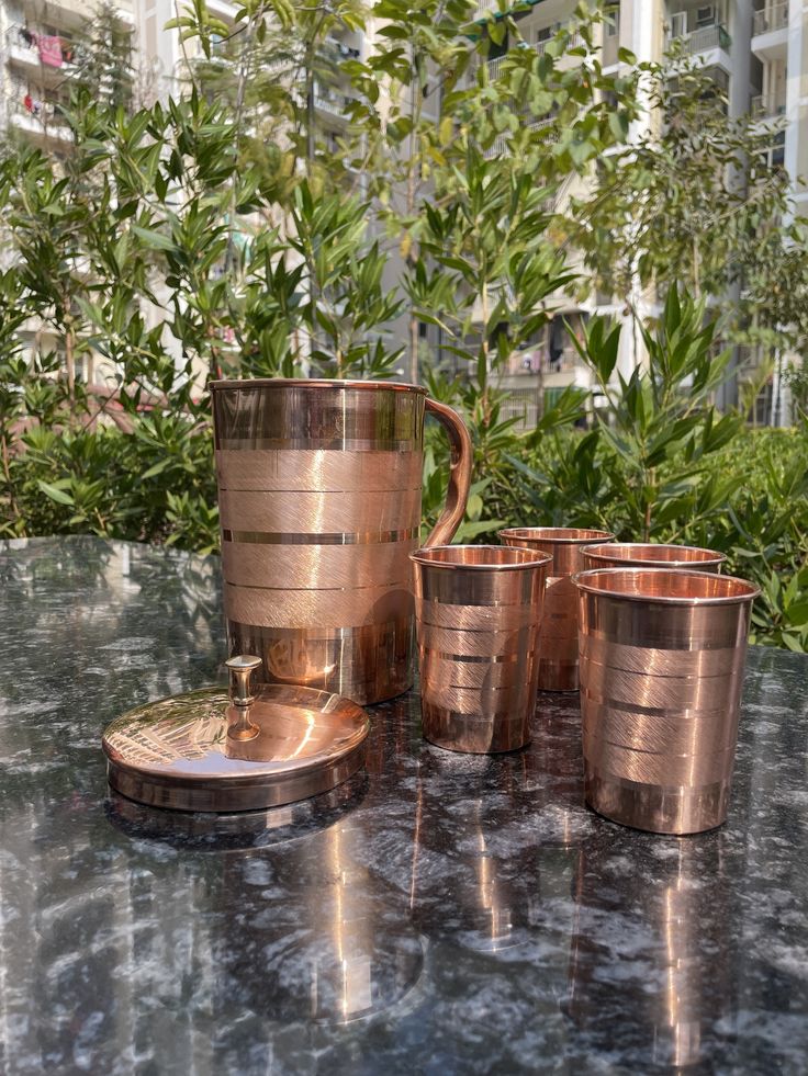 four copper cups sitting on top of a table next to each other and one is empty