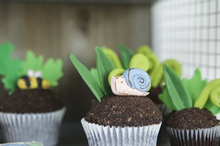 three cupcakes with grass and snails on them