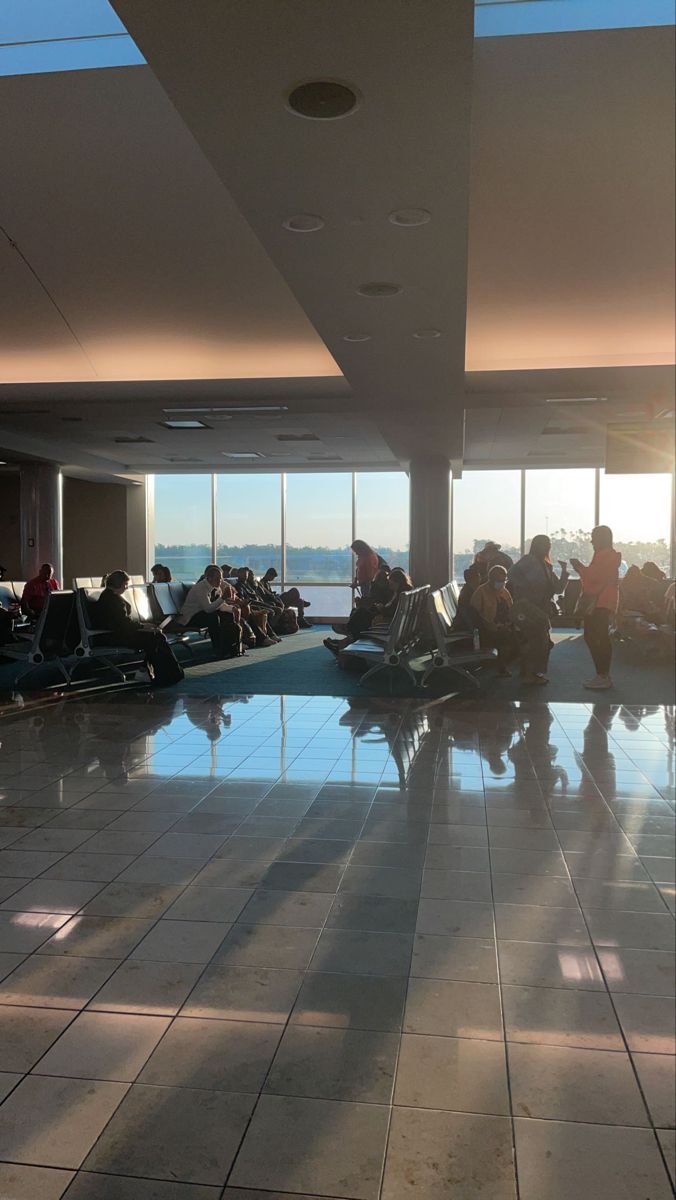 many people are sitting in an airport waiting for their luggage to come on the plane