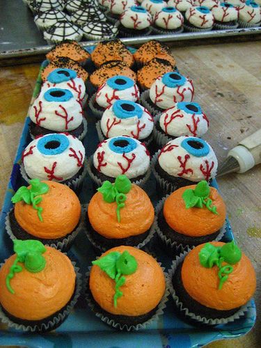 cupcakes are decorated with baseball balls and green leaves