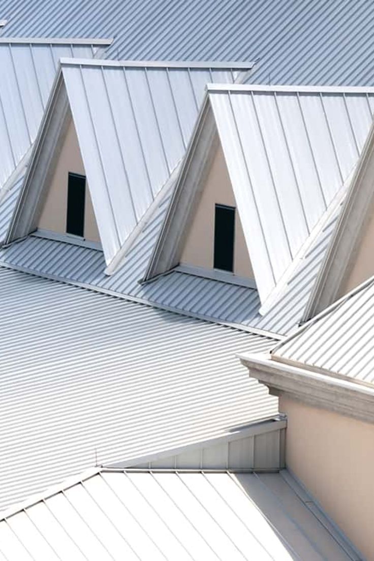 an airplane is sitting on the roof of a building that has three triangular shaped roofs