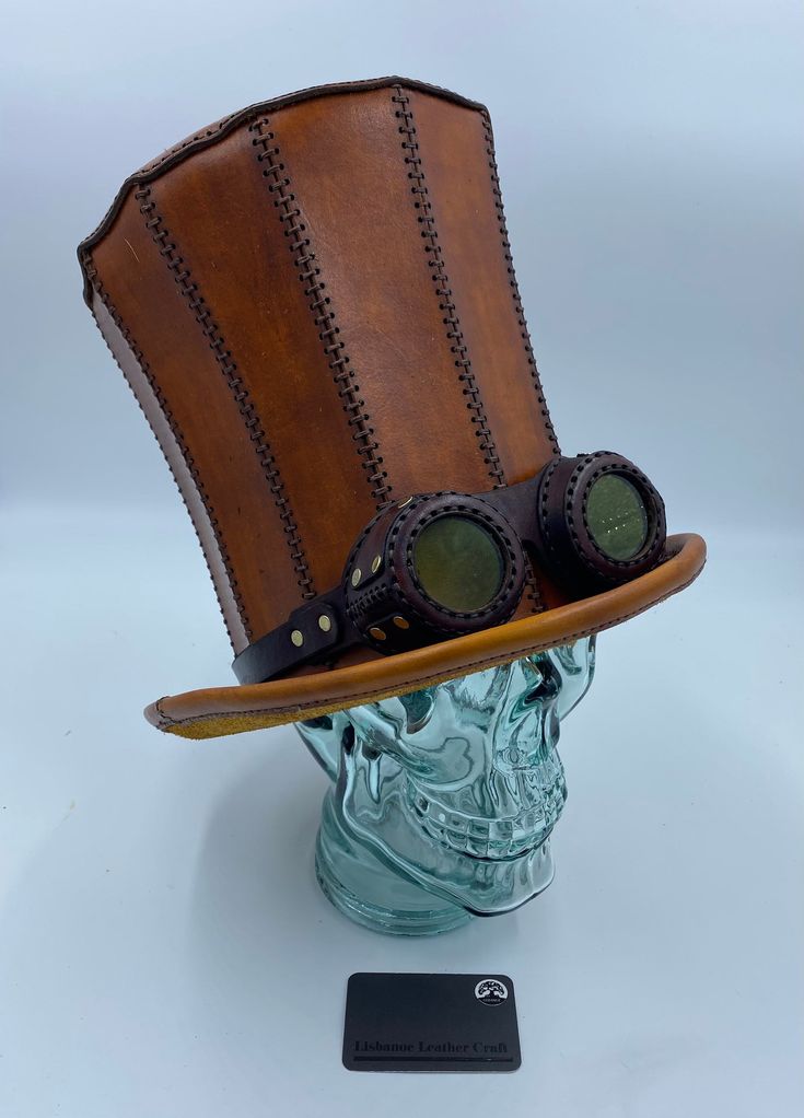 "This listing is for the actual item shown in the photos. It fits a head 23\" in circumference.  This listing shows the hat with a pair of steampunk goggles for decoration. The goggles are included with the hat.  I have another listing for this hat with a band including some little glass bottles and peacock feathers if you would prefer; see my other shop items.   This hat has a couple of interesting brand marks on the leather, one near the top and one partially hidden by the band. You can see th Steampunk High Crown Costume Accessories For Cosplay, Vintage High Crown Costume Hats For Cosplay, Steampunk Top Hat With High Crown For Themed Events, Steampunk High Crown Top Hat For Cosplay, Steampunk Costume Accessories With Brimmed Shape, Vintage Top Hat With High Crown For Cosplay, Vintage High Crown Top Hat For Cosplay, Vintage Brimmed Costume Accessories, Vintage Brown Costume Hats And Headpieces For Festival