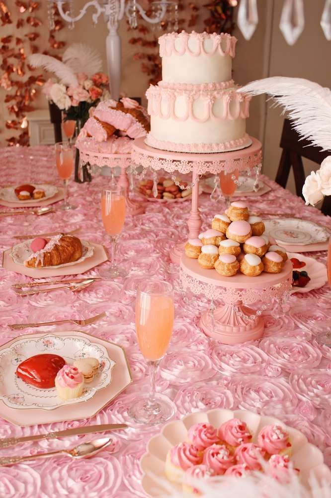 a table topped with lots of pink desserts and pastries on top of plates