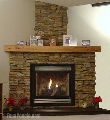 a fire place in a living room with flowers on the mantle and pictures above it