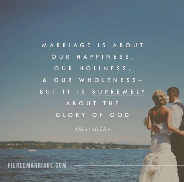 a man and woman standing next to each other on top of a rock near the ocean