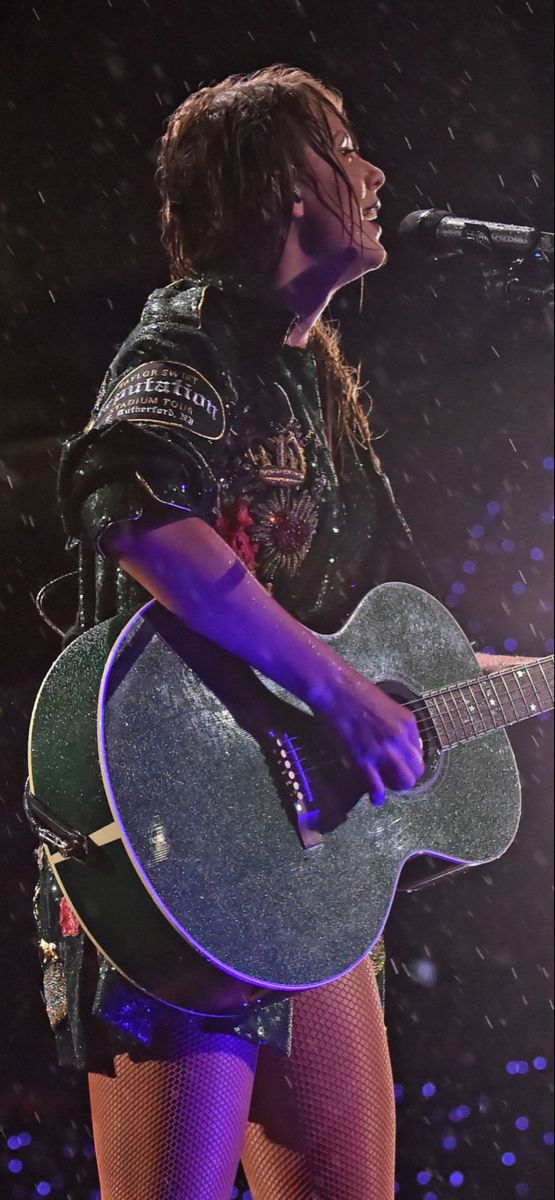 a woman with an acoustic guitar on stage