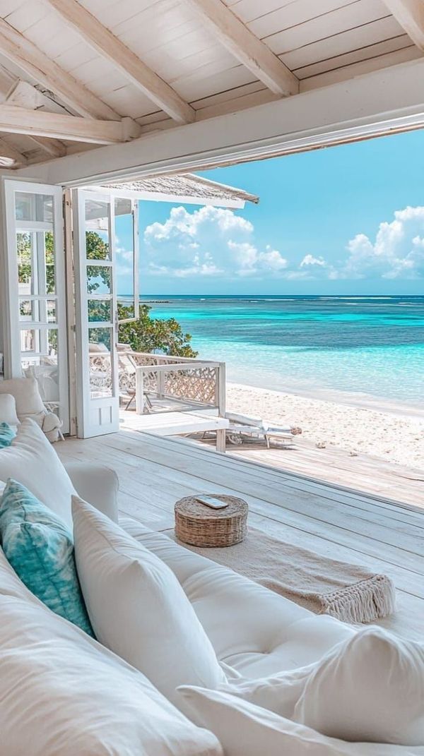 a large white couch sitting on top of a wooden floor next to an ocean view