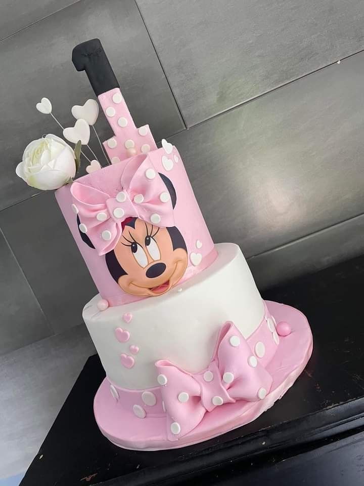 a pink and white cake with minnie mouse on top