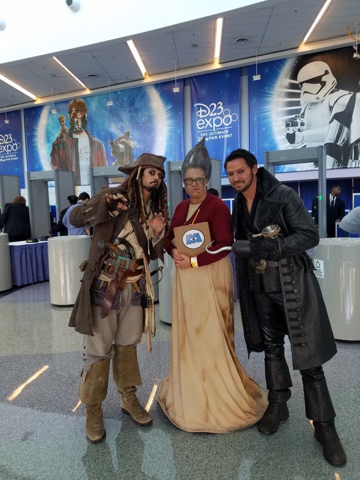 three people dressed up as pirates posing for a photo in an airport lobby with one holding a plaque