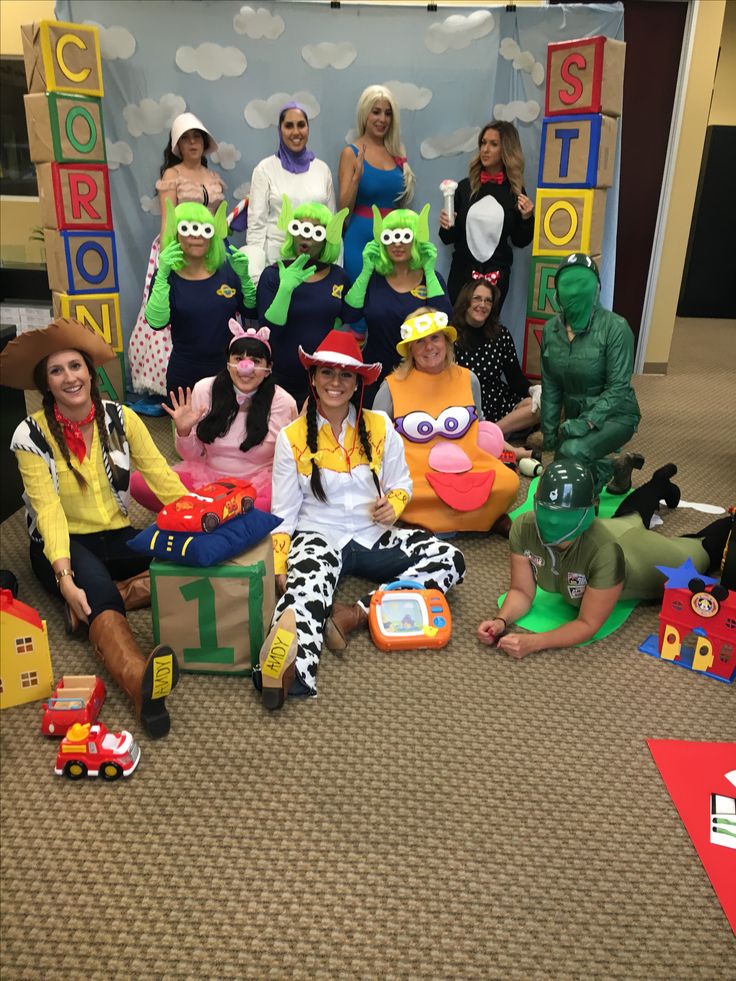 group of people dressed in costumes sitting on the floor next to each other and posing for a photo