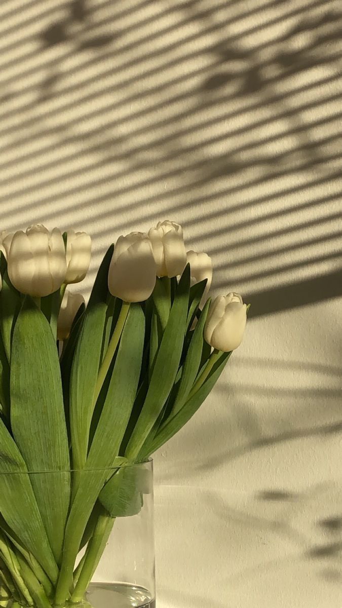 a glass vase filled with white flowers on top of a table