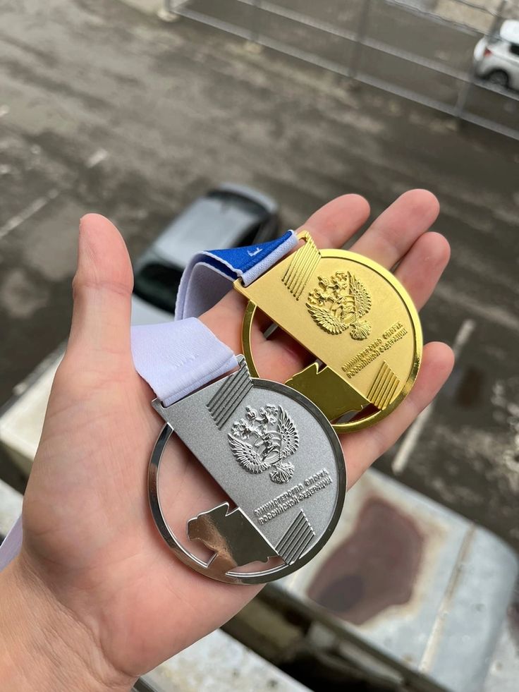 a person holding two medals in their hand, one is gold and the other is silver