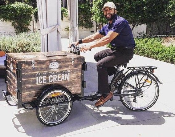 a man riding on the back of a bike with an ice cream cart