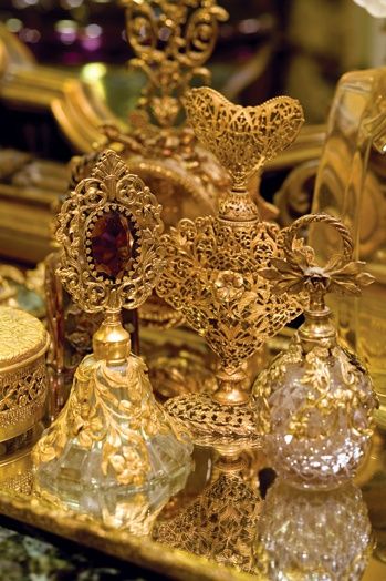 an assortment of perfume bottles on display in a gold case with other items around it