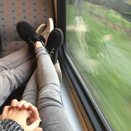 a person sitting on a train looking out the window with their feet propped up in front of them