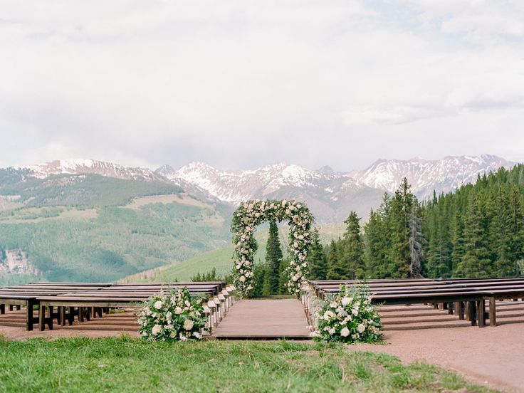 an outdoor ceremony set up in the mountains with flowers and greenery on the aisle