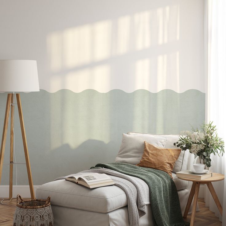 a white couch sitting next to a lamp on top of a hard wood floor under a window