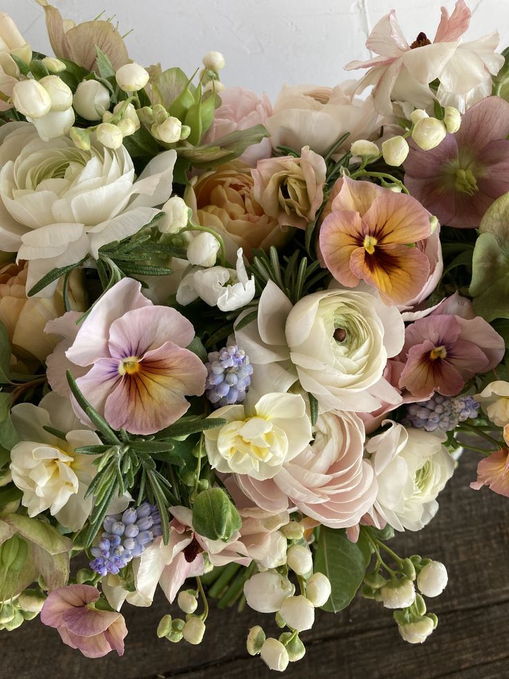 a bunch of flowers that are on top of a wooden table with white and pink flowers