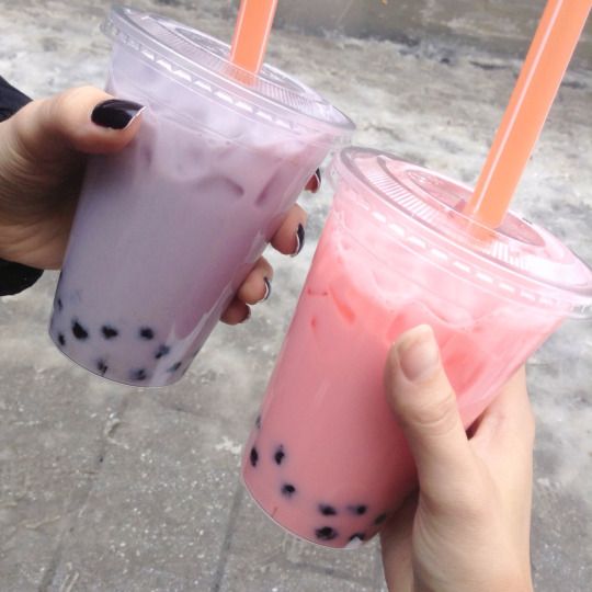 two people holding up drinks with straws in their hands and one is wearing black nail polish