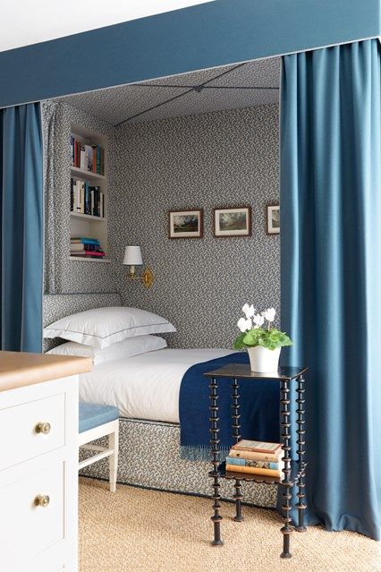 a bedroom with blue curtains and a bed in the corner next to a nightstand table