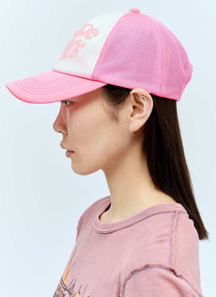 a young woman wearing a pink hat with white letters on the front and side of her face