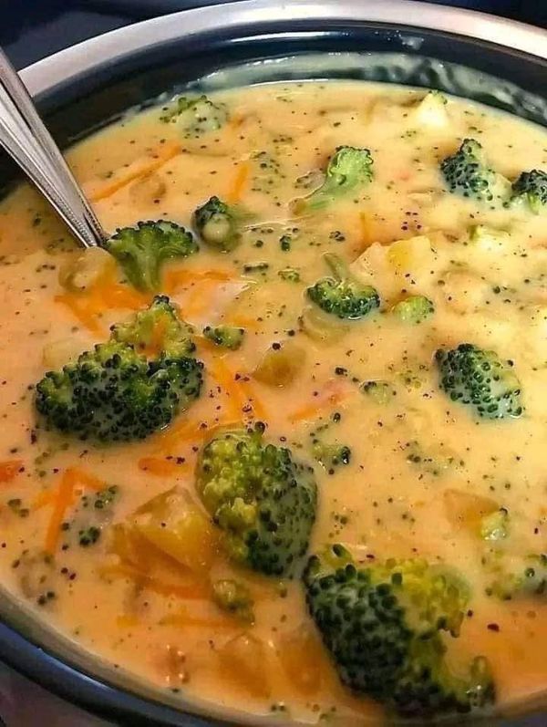 broccoli and cheese soup in a crock pot with a spoon sticking out