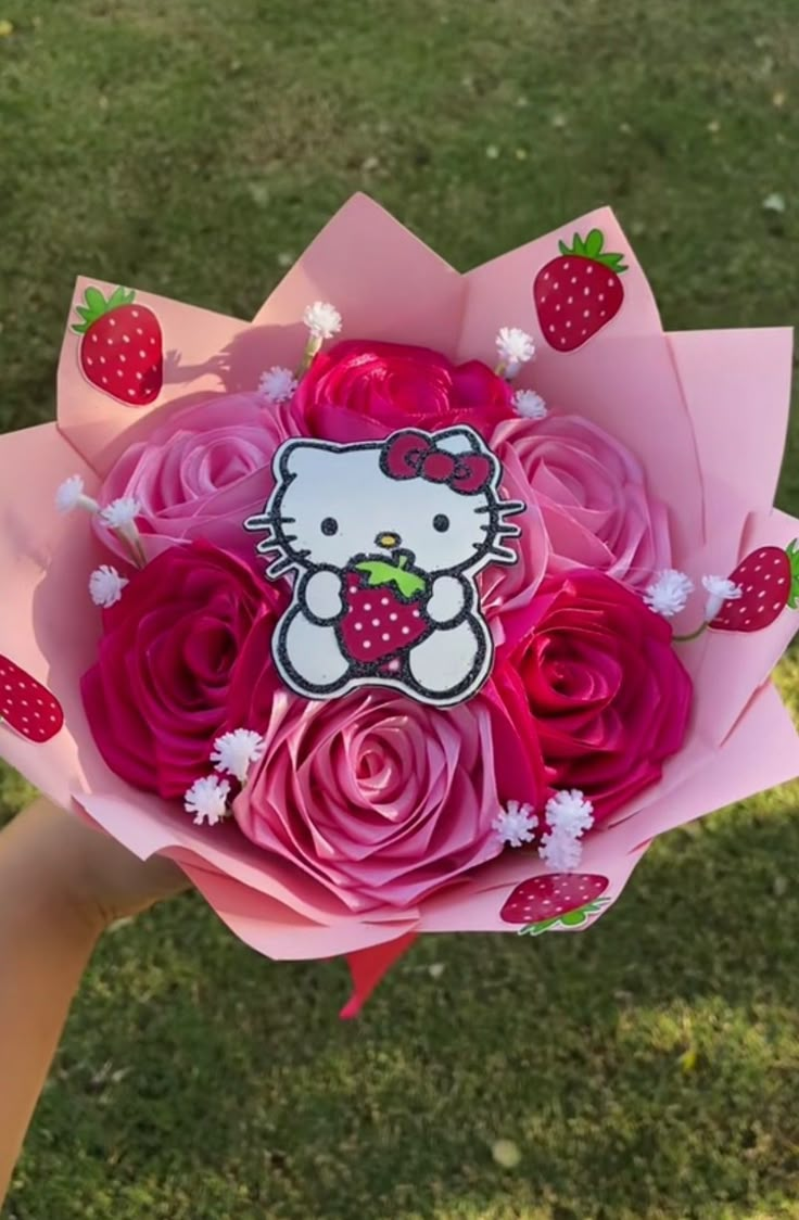 a hello kitty bouquet with pink roses and strawberries on it in someone's hand