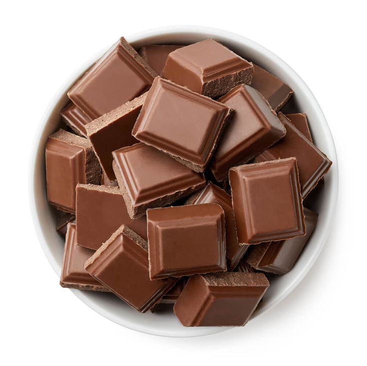 a bowl filled with chocolate pieces on top of a white table