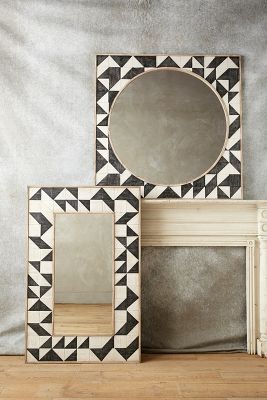 three mirrors sitting next to each other on top of a wooden floor near a fireplace