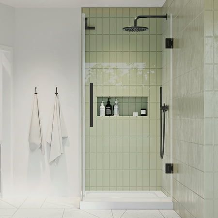 a white bathroom with green tiled walls and floor, two towels hanging on the wall