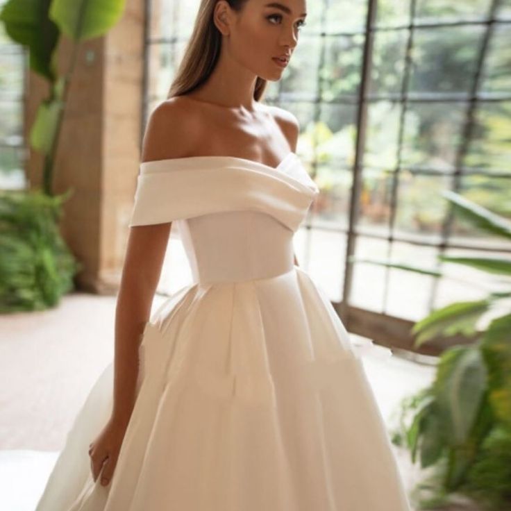 a woman in a white wedding dress is posing for the camera with her hand on her hip