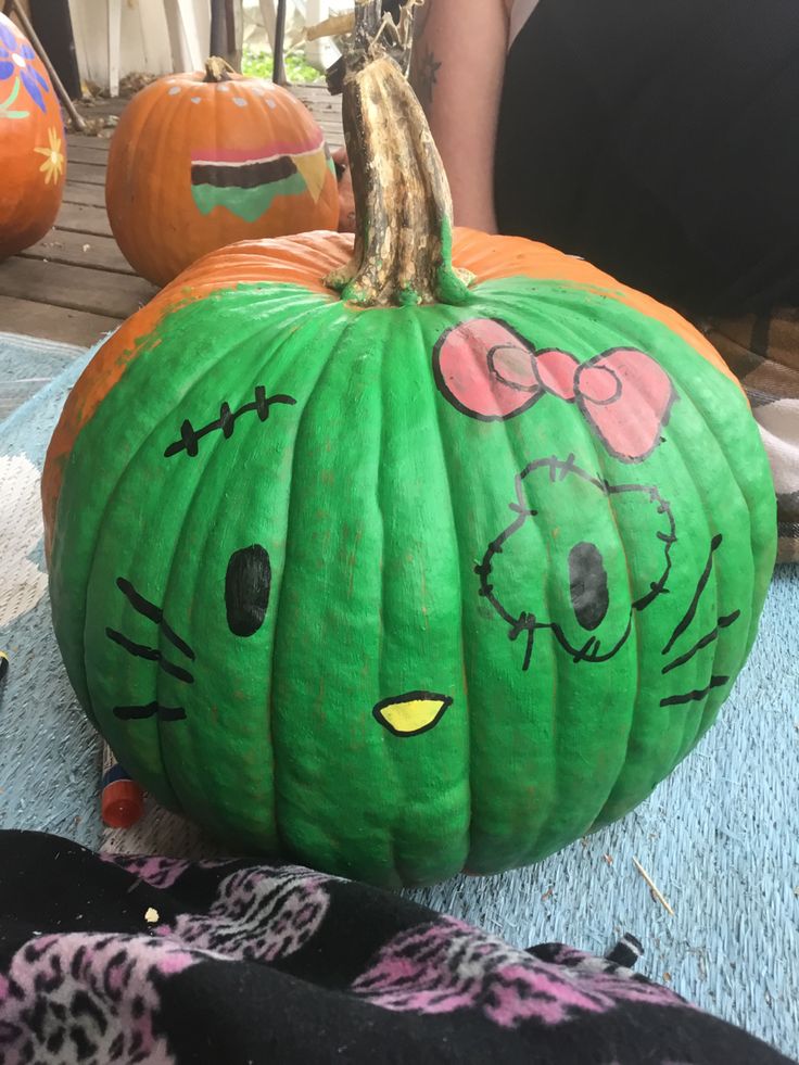 a green pumpkin with hello kitty faces painted on it