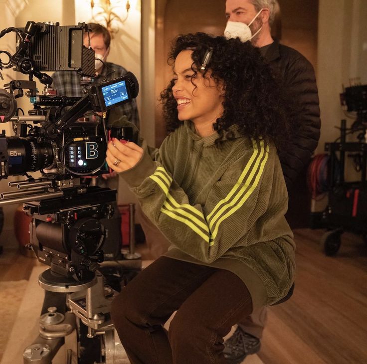 a woman sitting on top of a tripod in front of a camera