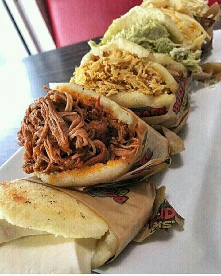 three sandwiches are lined up next to each other on a table with wrappers around them